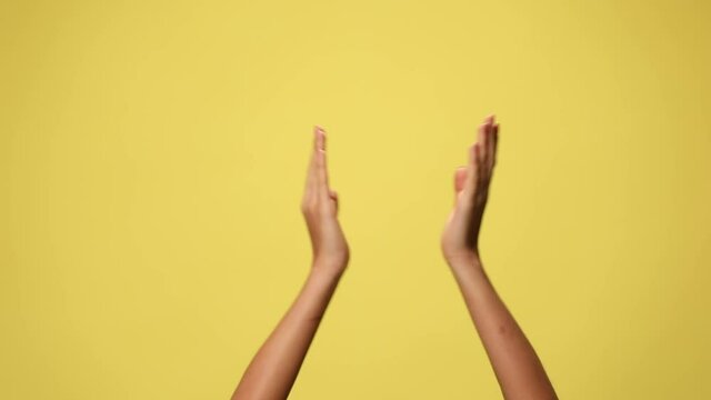 two hands clapping, pointing at the camera, pointing at each other and celebrating succes on yellow background