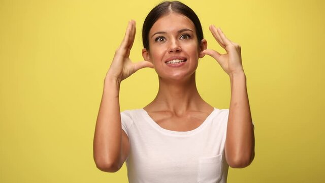 beautiful casual woman mimicking with her two hands that are babbling around and won't shut up on yellow background