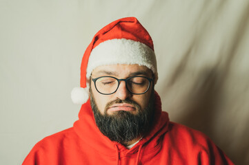 Annoyed man in Christmas hat exhales with closed eyes