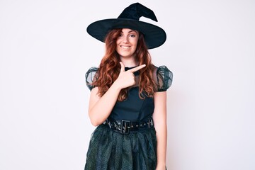 Young beautiful woman wearing witch halloween costume cheerful with a smile on face pointing with hand and finger up to the side with happy and natural expression