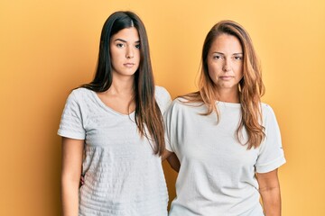 Hispanic family of mother and daughter wearing casual white tshirt relaxed with serious expression on face. simple and natural looking at the camera.