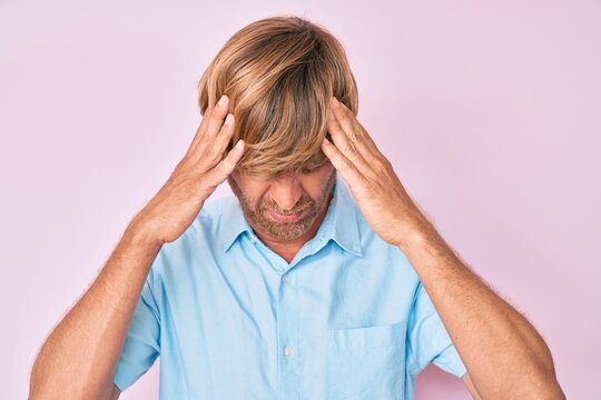 Young blond man wearing casual clothes with hand on head, headache because stress. suffering migraine.