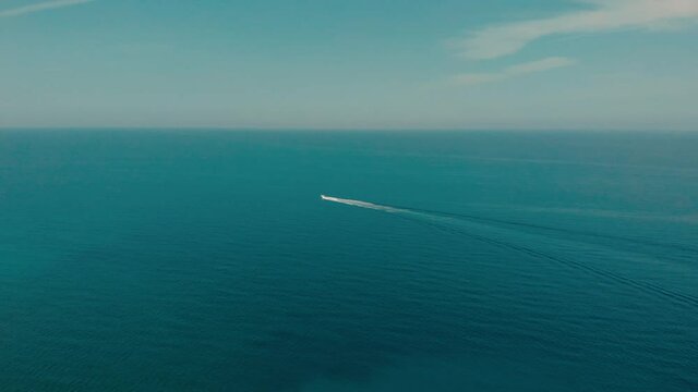 The sea and the sky. A small boat sails on the calm bkue surface of the sea.