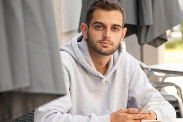Obraz premium young man with mobile phone sitting in cafe terrace