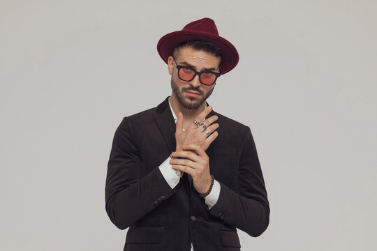 Charming fashion model arranging his sleeve, wearing hat and sunglasses