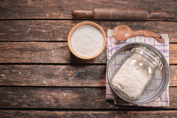 A flour in the jar and different kitchen utensils on the table background.