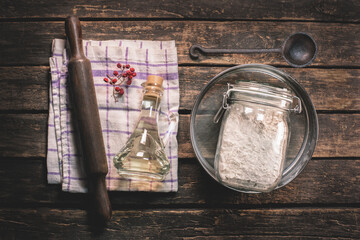 Flour in the glass jar, plunger, sifter and cooking oil on the kitchen table background.