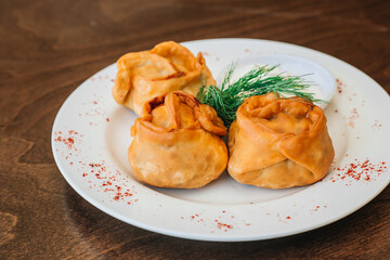 Russian kitchen. Baked manti with meat. The dish stands on a dark wooden background. Minced dough