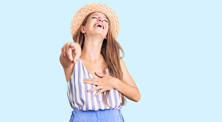 Young beautiful blonde woman wearing summer hat laughing at you, pointing finger to the camera with hand over body, shame expression