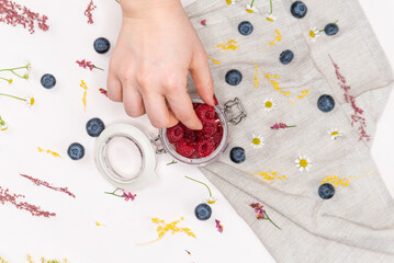 Raspberries inside a jar from above with a woman's hand