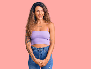 Young hispanic woman with tattoo wearing casual clothes winking looking at the camera with sexy...
