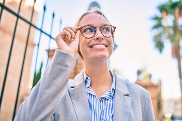 Young blonde businesswoman smiling happy walking at the city.