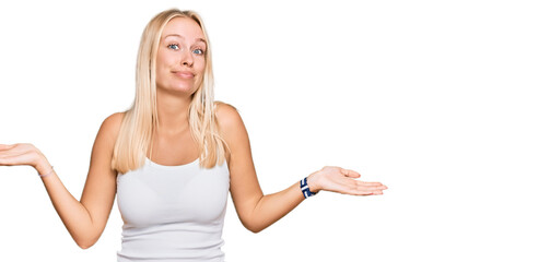 Young blonde girl wearing casual style with sleeveless shirt clueless and confused expression with arms and hands raised. doubt concept.