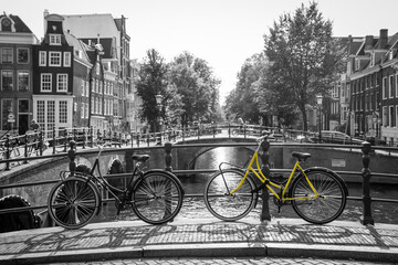 A picture of a lonely yellow bike on the bridge over the channel in Amsterdam. The background is...