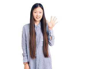 Young beautiful chinese woman wearing casual shirt showing and pointing up with fingers number five while smiling confident and happy.