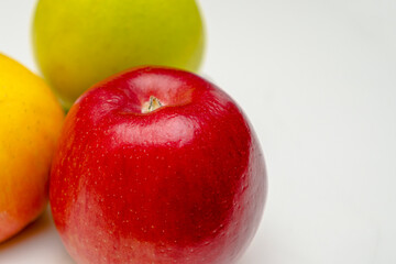 A red ripe apple lies on the table, on a white background, close-up.
