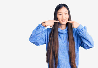 Young beautiful chinese woman wearing casual turtleneck sweater smiling cheerful showing and pointing with fingers teeth and mouth. dental health concept.