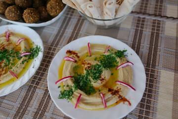 A table spread of middle-eastern dishes like hummus and falafel and salad
