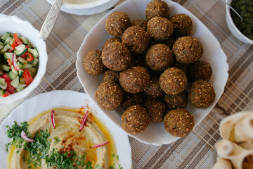 A table spread of middle-eastern dishes like hummus and falafel and salad
