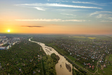 Sunset over rural area in town with wide river and yellow sun.