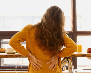 Back view of faceless young woman touching back feeling backache, discomfort low lumbar muscular...