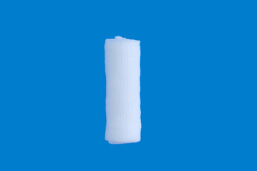 Rolled up medical cotton bandage on blue background. View from above.