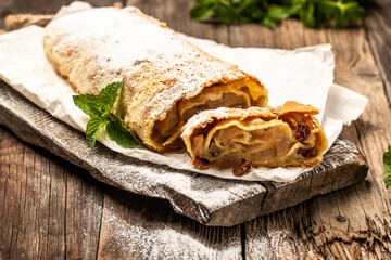 Homemade traditional Apple strudel powdered sugar on a wooden background. Christmas homemade pastry