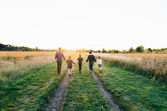 Family holding hands and walking towards sunset