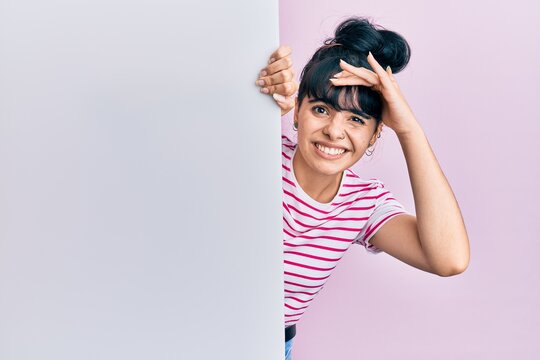 Young hispanic girl holding blank empty banner stressed and frustrated with hand on head, surprised and angry face