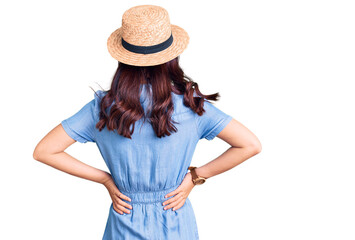 Young beautiful chinese girl wearing summer hat standing backwards looking away with arms on body