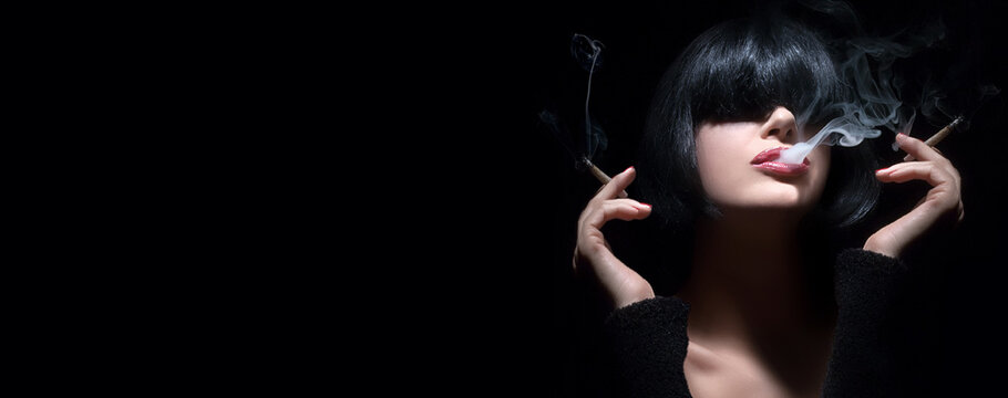 Closeup portrait of a sensual woman with bangs smoking with a cigarette in each hand