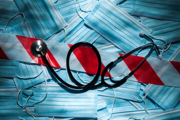 Coronavirus COVID-19 surgical face masks background with warning tape and stethoscope as abstract...
