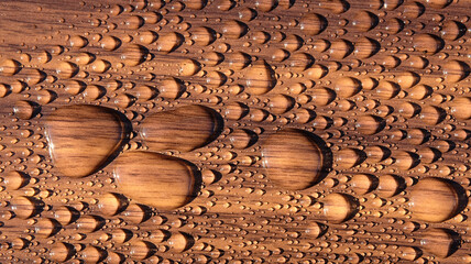 Water beads on a dark wood surface