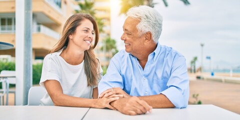 Obraz premium Middle age couple in love sitting at the terrace of coffee shop happy and cheerful together