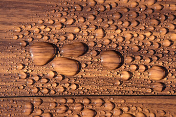 Water beads on a dark wood surface