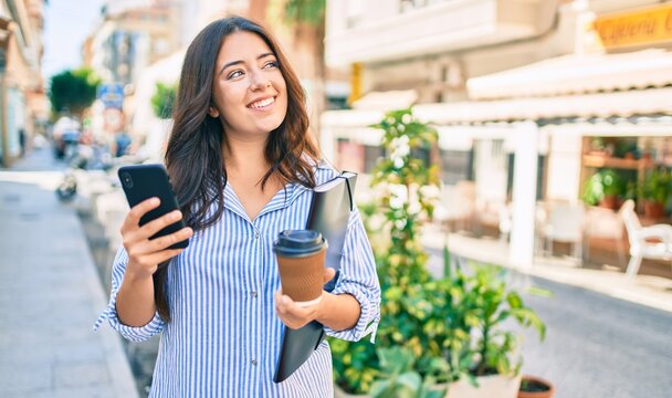 Young hispanic businesswoman using smartphone and drinking take away coffee at the city.