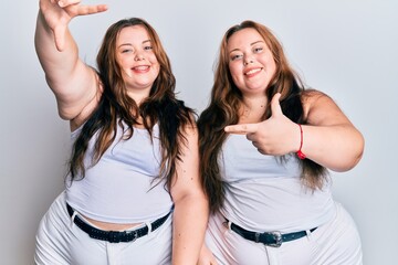 Fototapeta na wymiar Plus size caucasian sisters woman wearing casual white clothes smiling making frame with hands and fingers with happy face. creativity and photography concept.