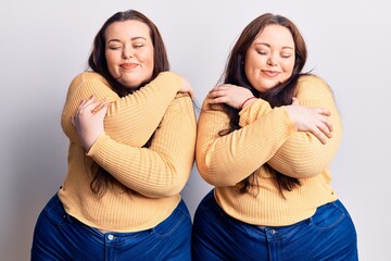 Young plus size twins wearing casual clothes hugging oneself happy and positive, smiling confident....