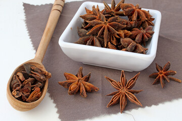 Portion of star anise in a wooden spoon and porcelain vase