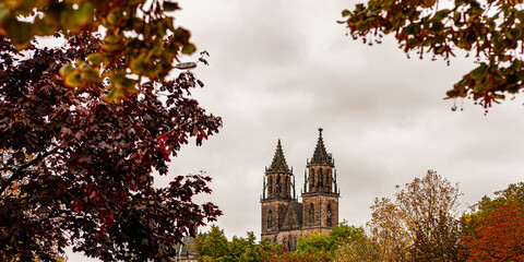 Türme des Doms St. Mauritius und St. Katharina in Magdeburg umrahmt von buntem Herbstlaub
