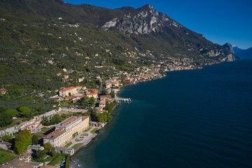 Fototapeta na wymiar Villa on Lake Garda in the background Alps and blue sky. Panoramic view of the Villa in the town of Gargnano on Lake Garda Italy. High-altitude aerial view of the architecture on Lake Garda.