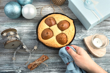 A woman's hand puts a pear pie on the Christmas table decorated in blue tones. The view from the top. The concept of Christmas and New year.