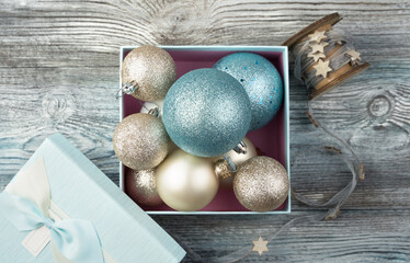 A set of Christmas balls of different colors in a blue gift box with a lid on a wooden background. The view from the top. The Concept Of A New Year.