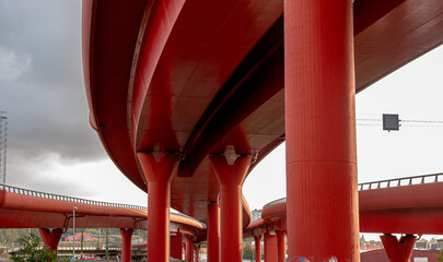 Two tall red road viaducts joining.