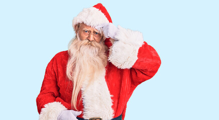 Old senior man with grey hair and long beard wearing traditional santa claus costume pointing unhappy to pimple on forehead, ugly infection of blackhead. acne and skin problem