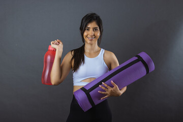 Retrato de joven mujer mexicana con tapete de yoga pilates y botella de agua