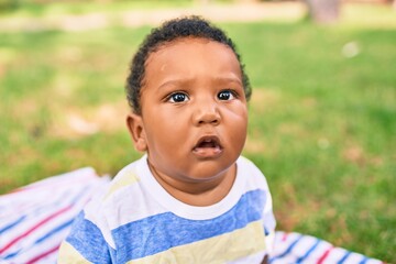 Adorable african american chubby toddler sitting on the grass at the park.