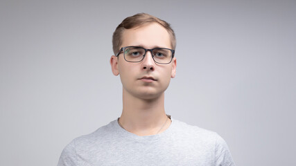 Close-up portrait of a business man with glasses, looking at the camera with a serious face, isolated on a white-gray background