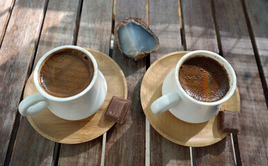 Turkish coffee with foam on top , made of fresh roasted and fine ground coffee beans, served in small ceramic cups on bamboo plates with Turkish delight or bitter chocolate pieces after breakfast