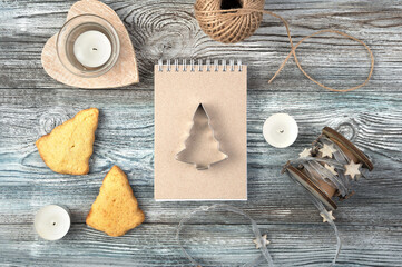 Christmas background with Notepad, iron shape of Christmas tree, cookies and candles on a wooden table. The view from the top. The concept of New year and Christmas.